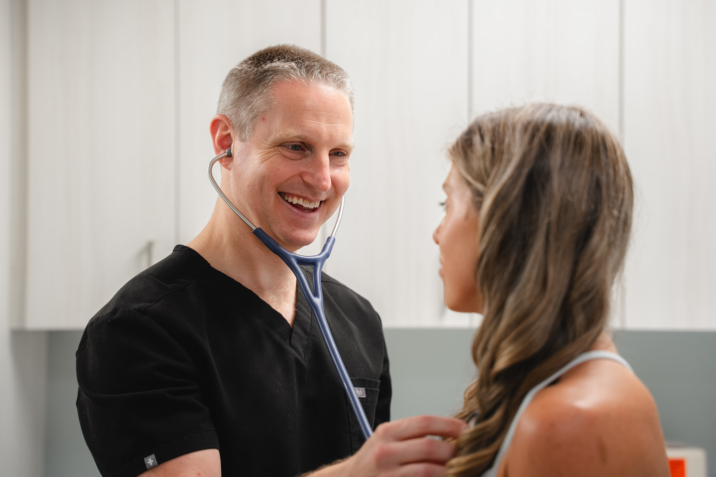 Dr. Schaaf smiling while using a stethoscope during an examination.