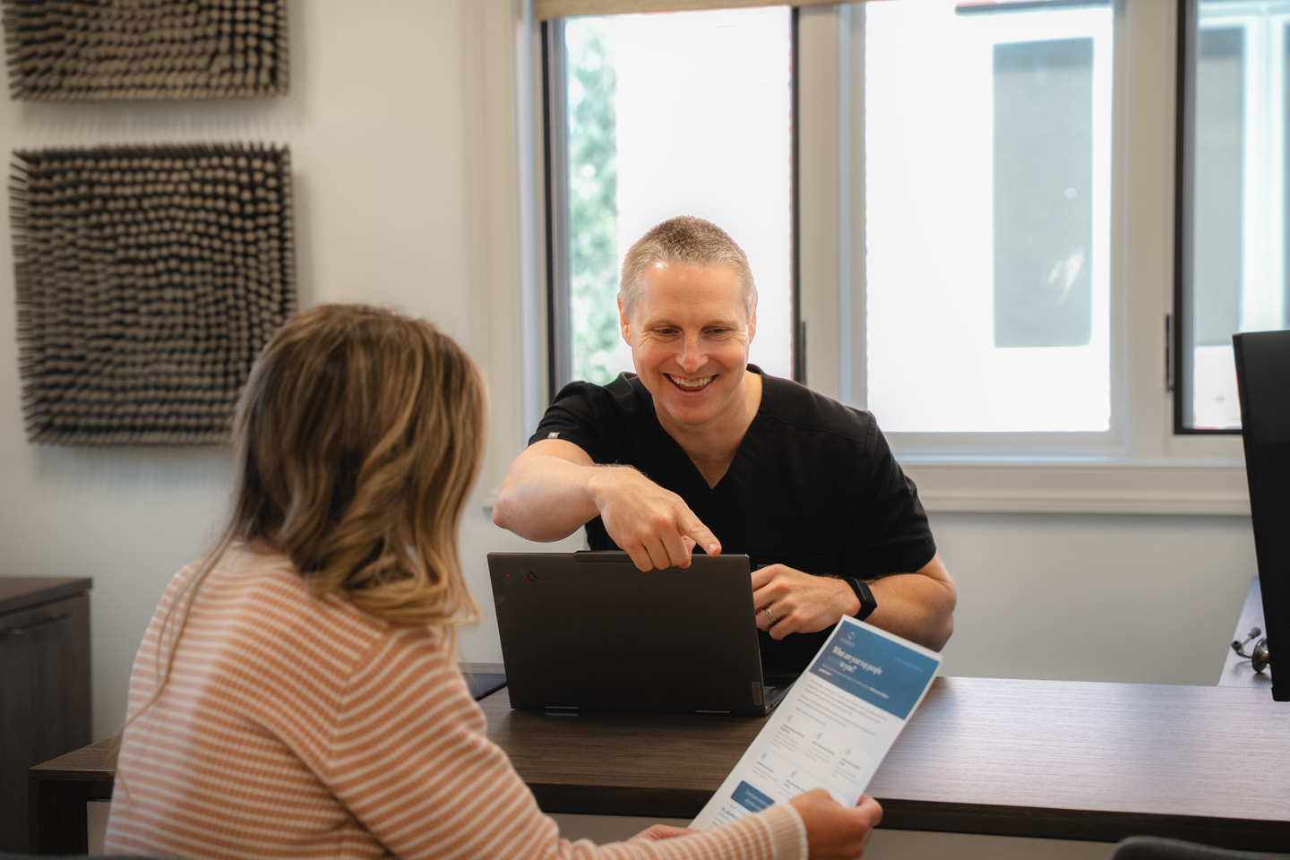 Dr. Schaaf discussing care across a desk, with a Continuum brochure in the foreground.